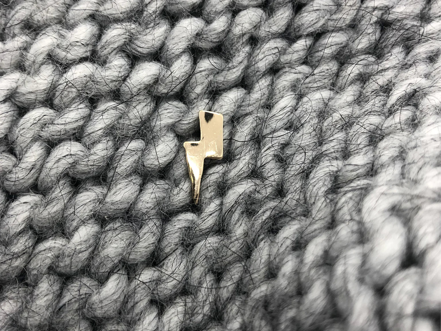 gold plated handmade lightning bolt pin by Typealive, on grey knit