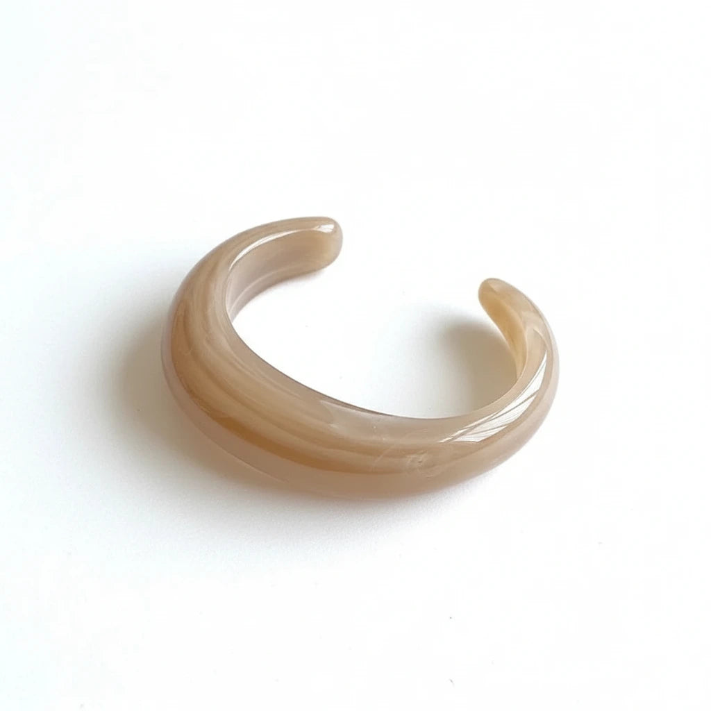 Caramel colored resin cuff bracelet on white surface