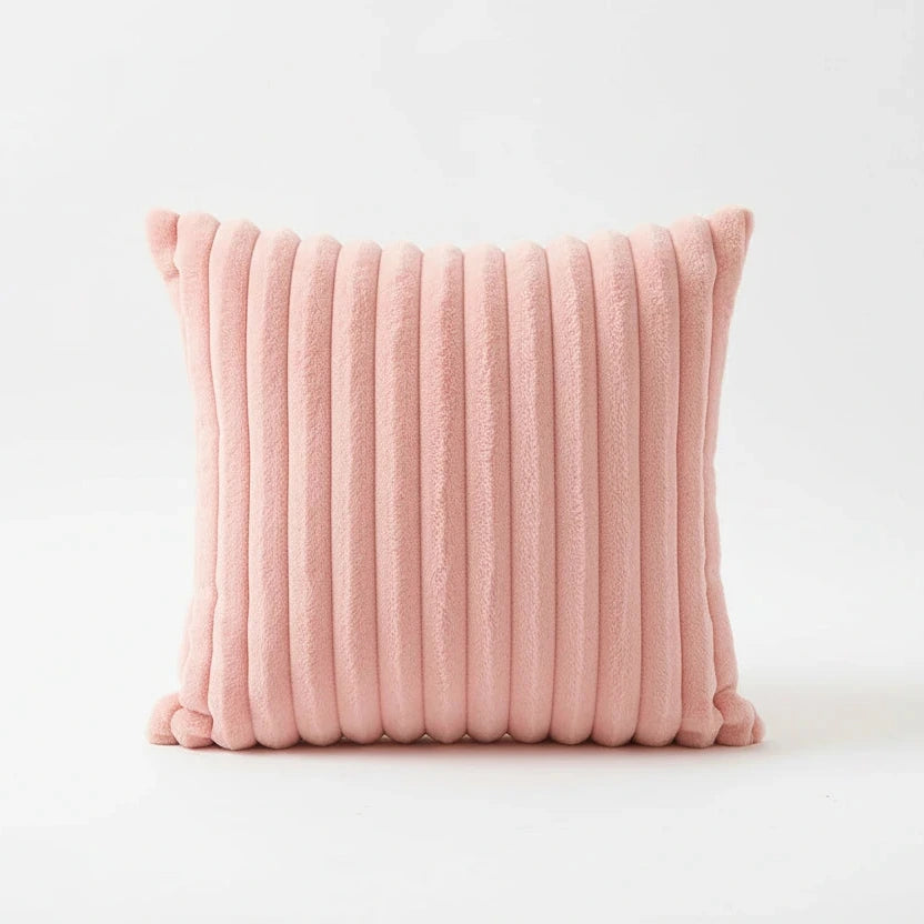 Pink textured pillow on a surface with a blurred background