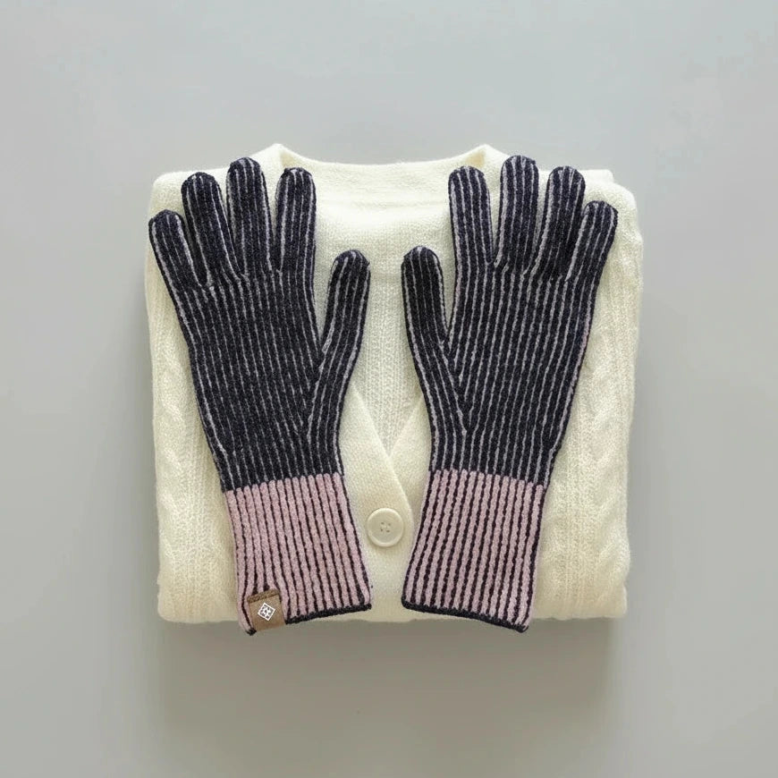 Pair of dark blue gloves on a folded white sweater against a gray background