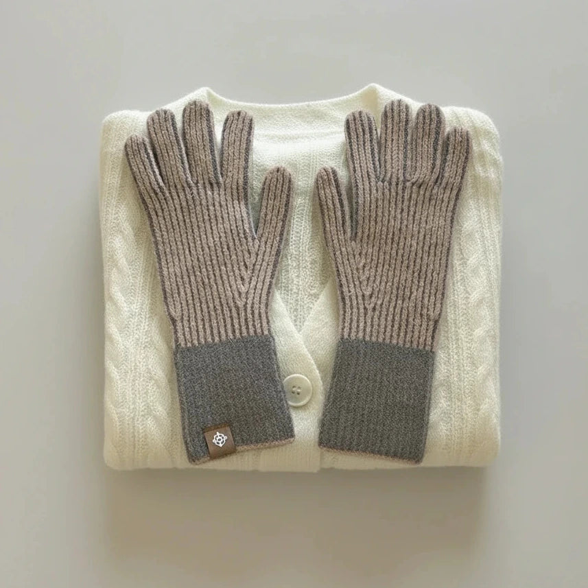 Pair of gray gloves on a white sweater on a light grey background