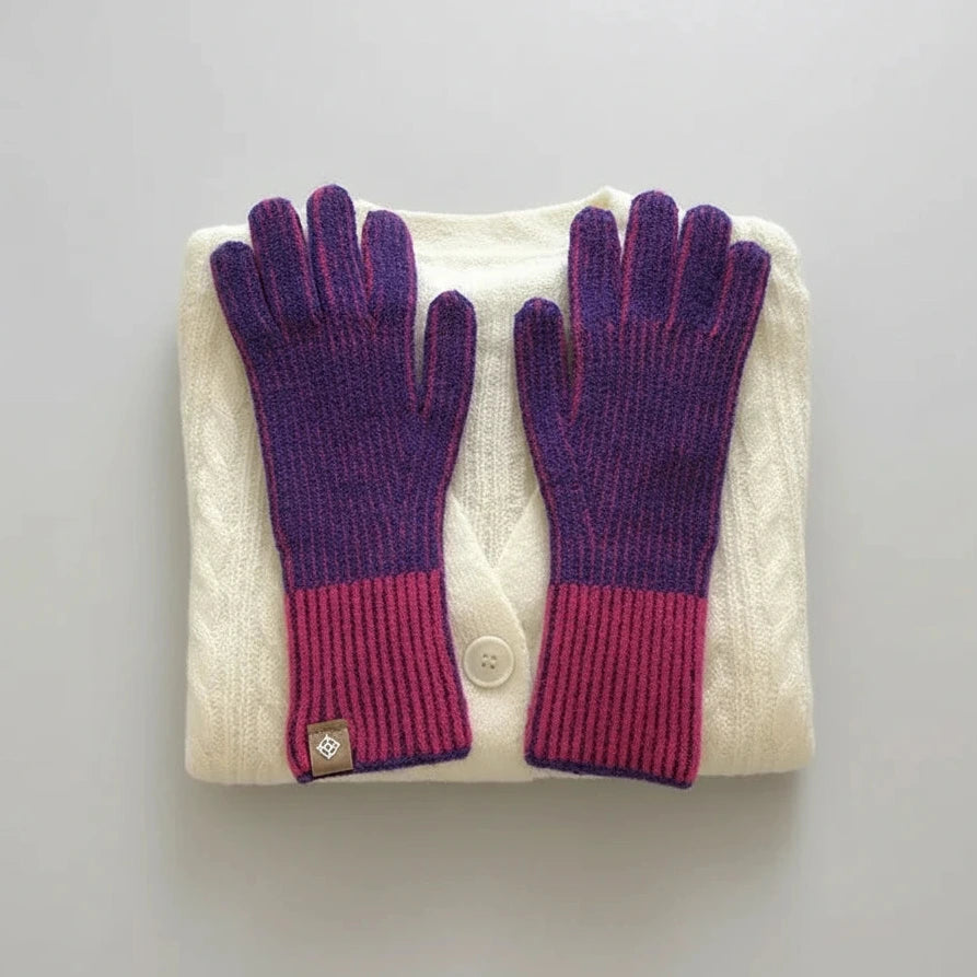 Pair of purple gloves on a folded white sweater with a gray background
